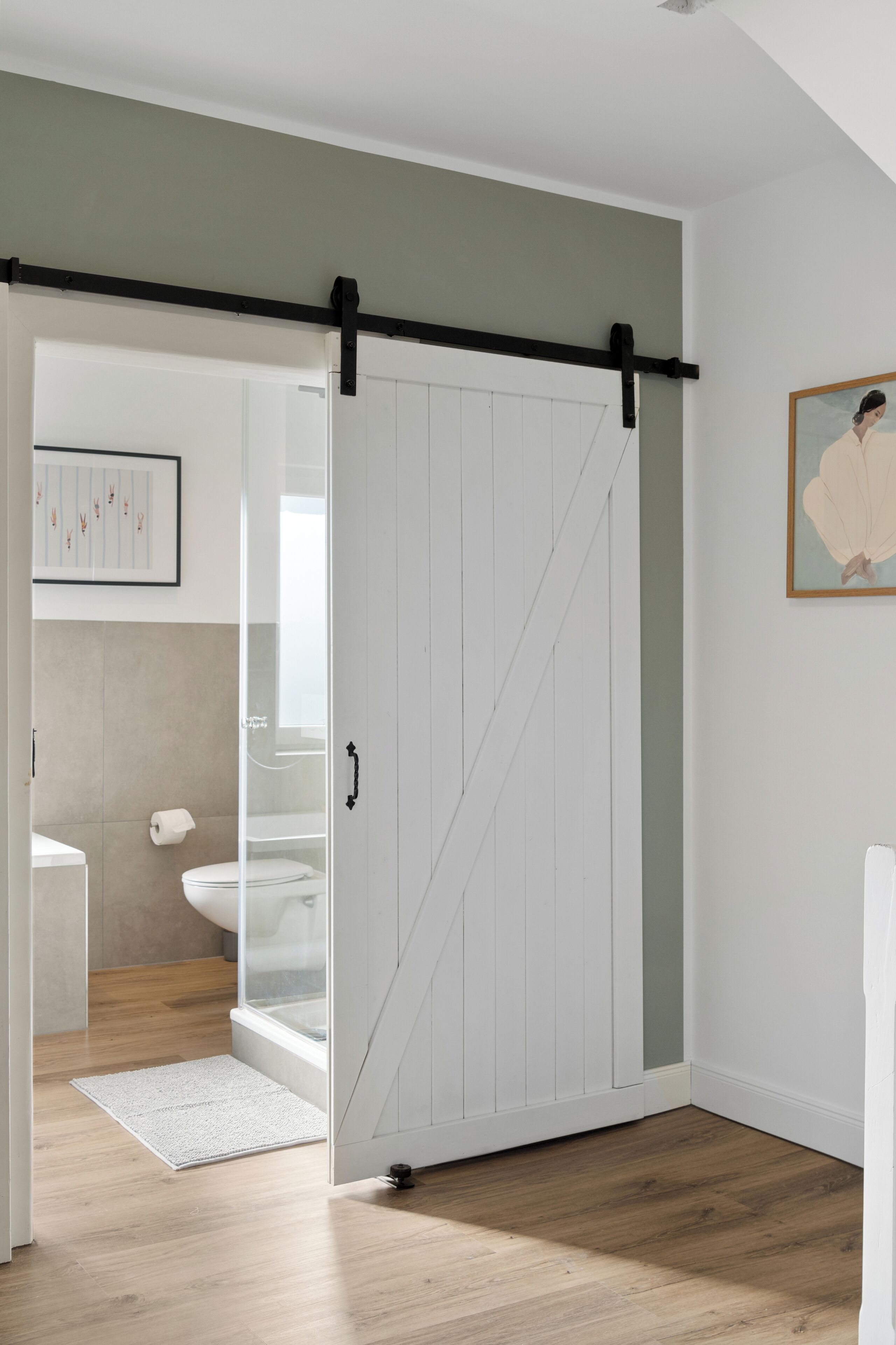 Ein modernes Badezimmer mit Toilette, einer Duschkabine aus Glas und Holzboden.
