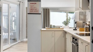 Una cocina moderna con armarios de colores claros, una lámpara colgante y un letrero en la pared.
