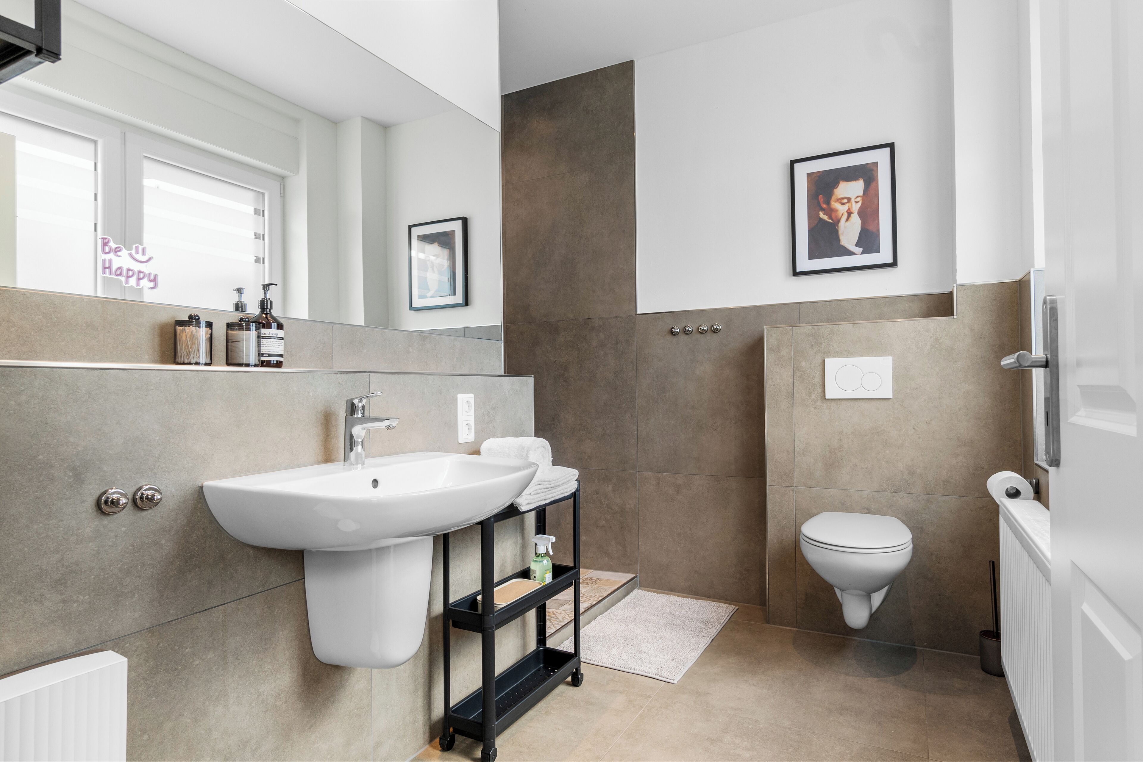 Un bany modern amb un lavabo gran, un vàter i una zona de dutxa.