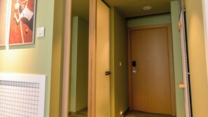 Un pasillo con una puerta de madera, un cuadro en la pared y un interruptor de luz.