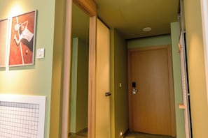 Un pasillo con una puerta de madera, un cuadro en la pared y un interruptor de luz.