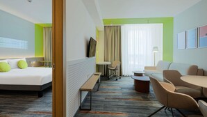 A hotel room with a bed, a desk, a chair, a sofa, and a window with curtains. - ibis Styles Chisinau (Bacioi)