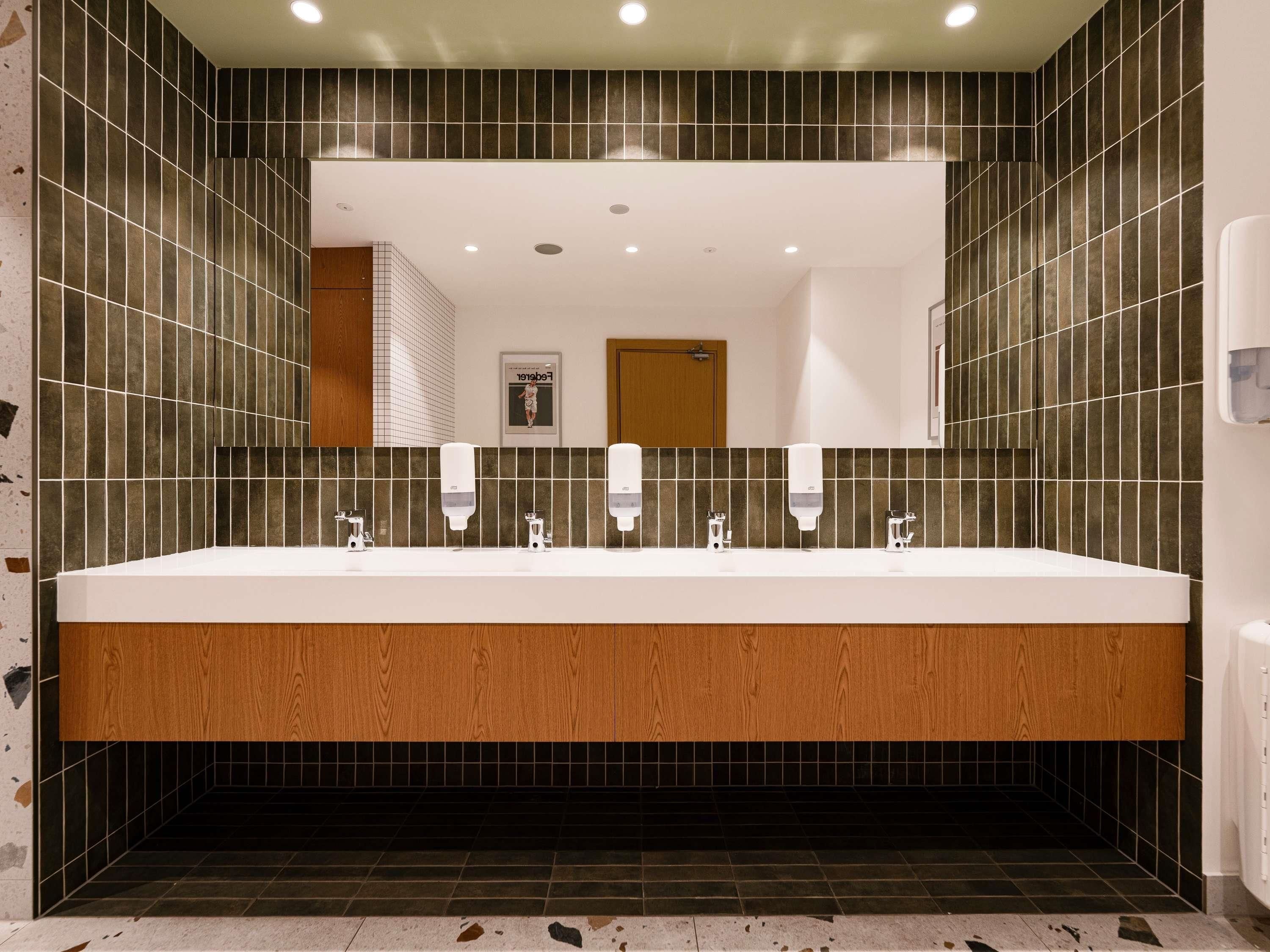 A modern bathroom with a large sink, multiple faucets, and a mirror above.