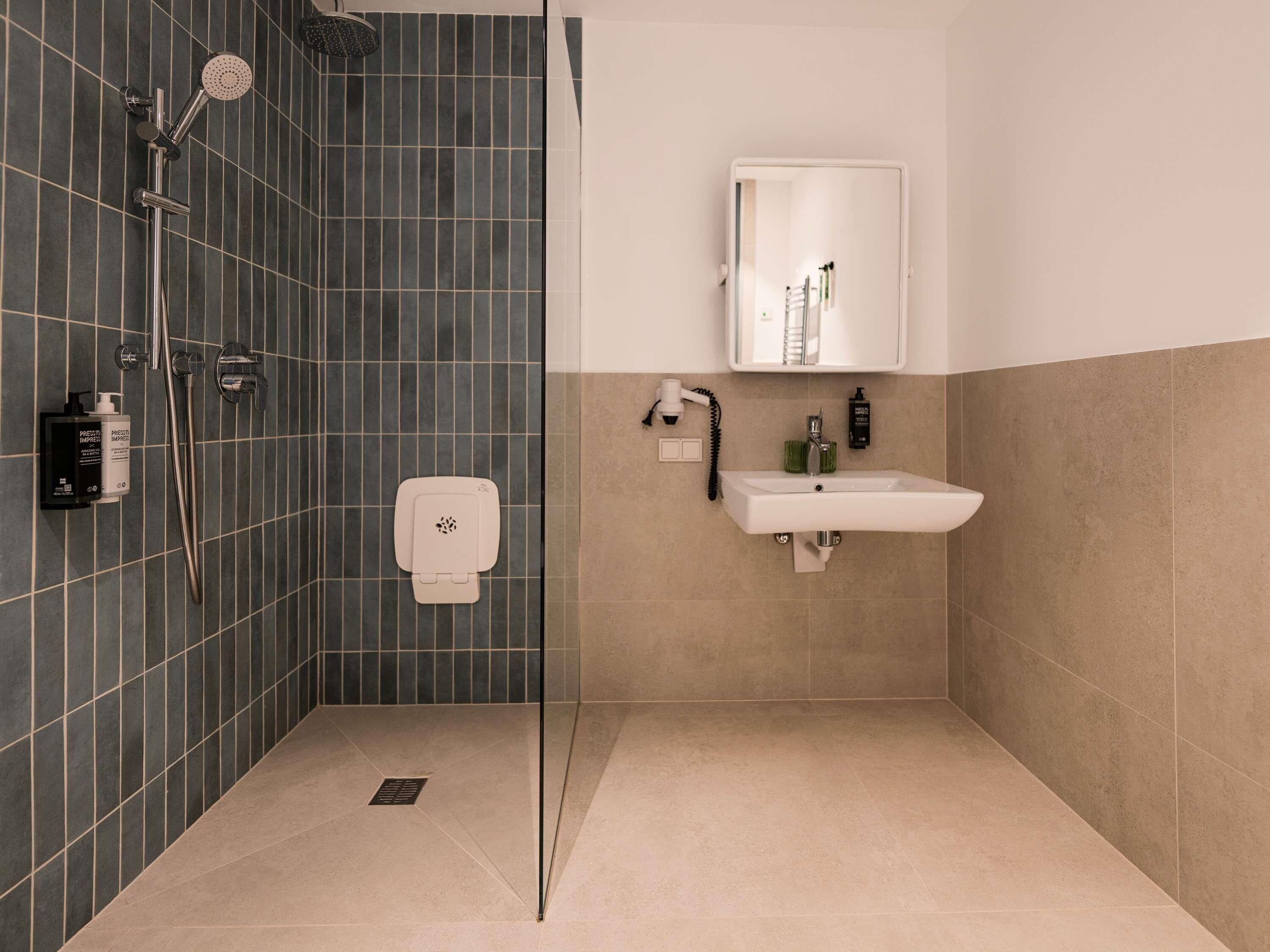 A bathroom with a shower, a sink, a mirror, and a toilet.