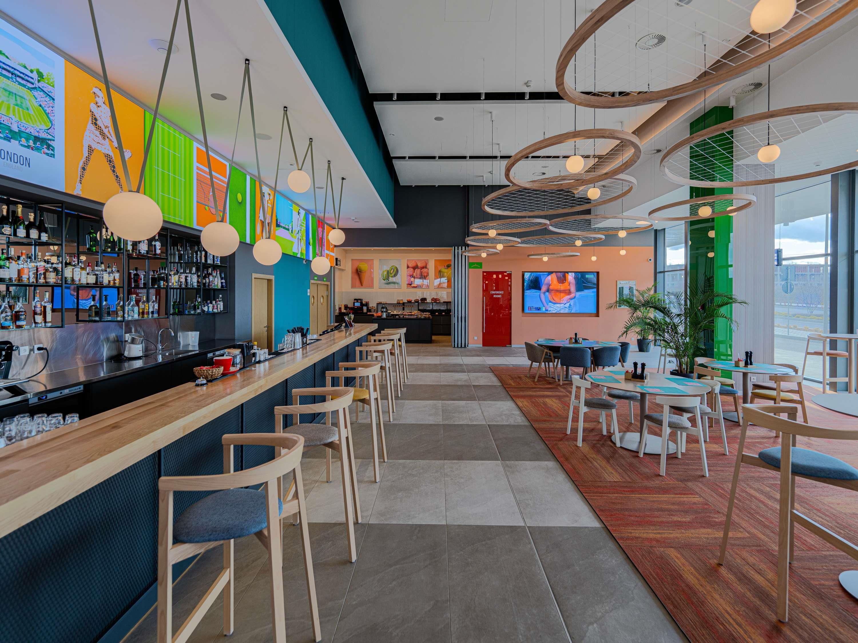 Un bar moderne doté d’un long comptoir, de nombreux tabourets et d’une grande variété de bouteilles.
