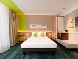 A modern hotel room with a large bed, bedside tables, a desk, and a wall-mounted TV. - ibis Styles Chisinau (Bacioi)