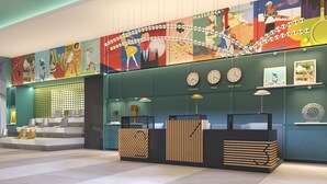 Un vestíbulo moderno con un mural colorido, una recepción y relojes que muestran diferentes ciudades.