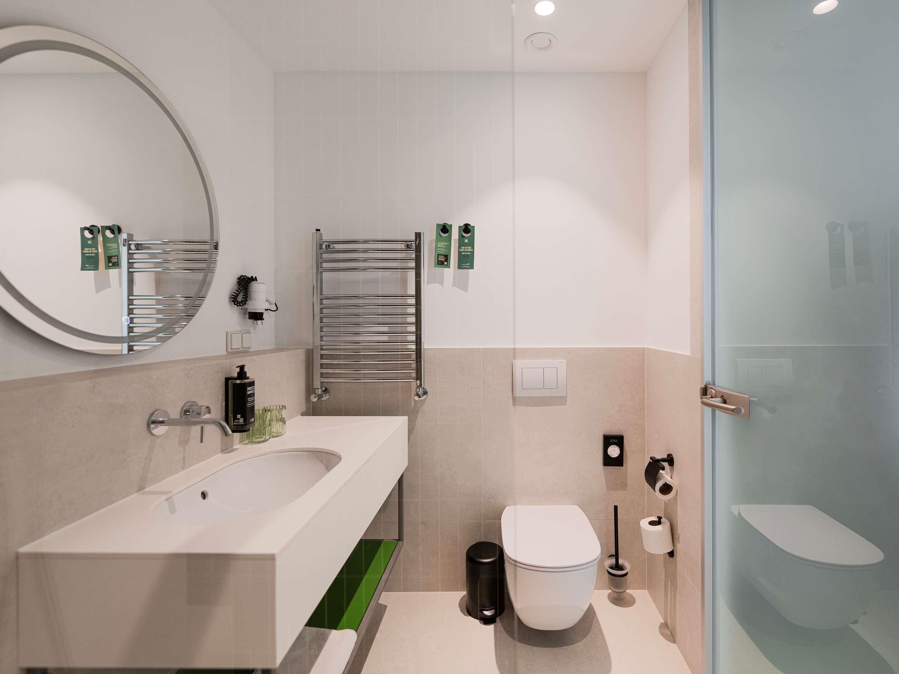 A modern bathroom with a bathtub, toilet, and glass shower enclosure.