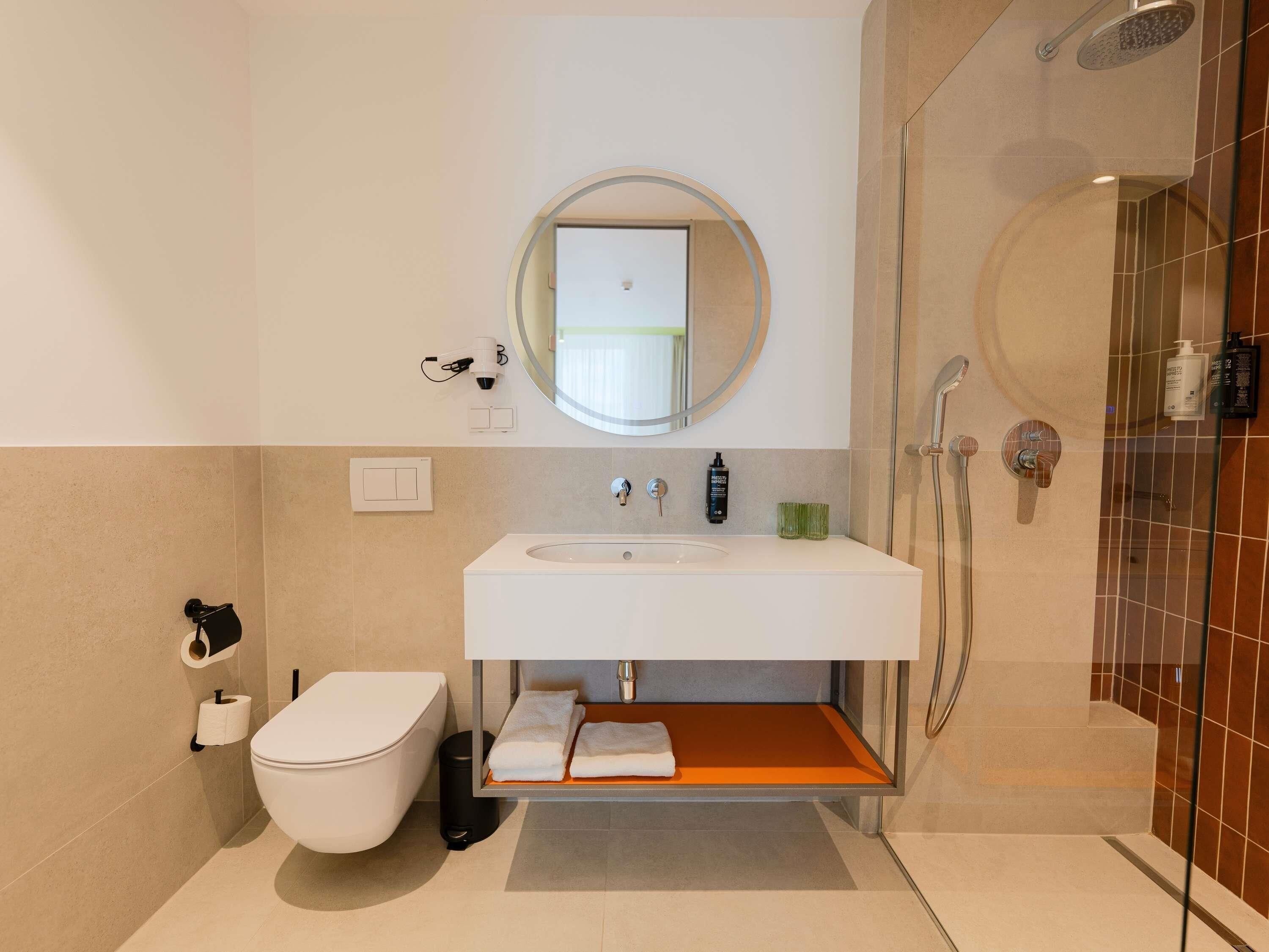 A modern bathroom with a toilet, sink, and shower.