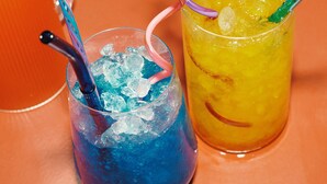 Dos vasos de bebidas heladas con pajitas de colores sobre una mesa.