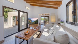 Un salon moderne avec une table en bois, un canapé, un téléviseur et une vue sur un paysage côtier.