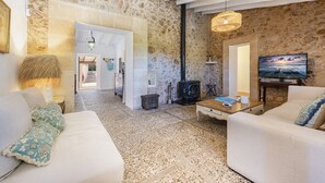 Un salon chaleureux avec un mur en pierre, une cheminée, un téléviseur et un canapé.