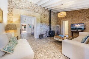 A cozy living room with a stone wall, a fireplace, a television, and a sofa with decorative pillows.