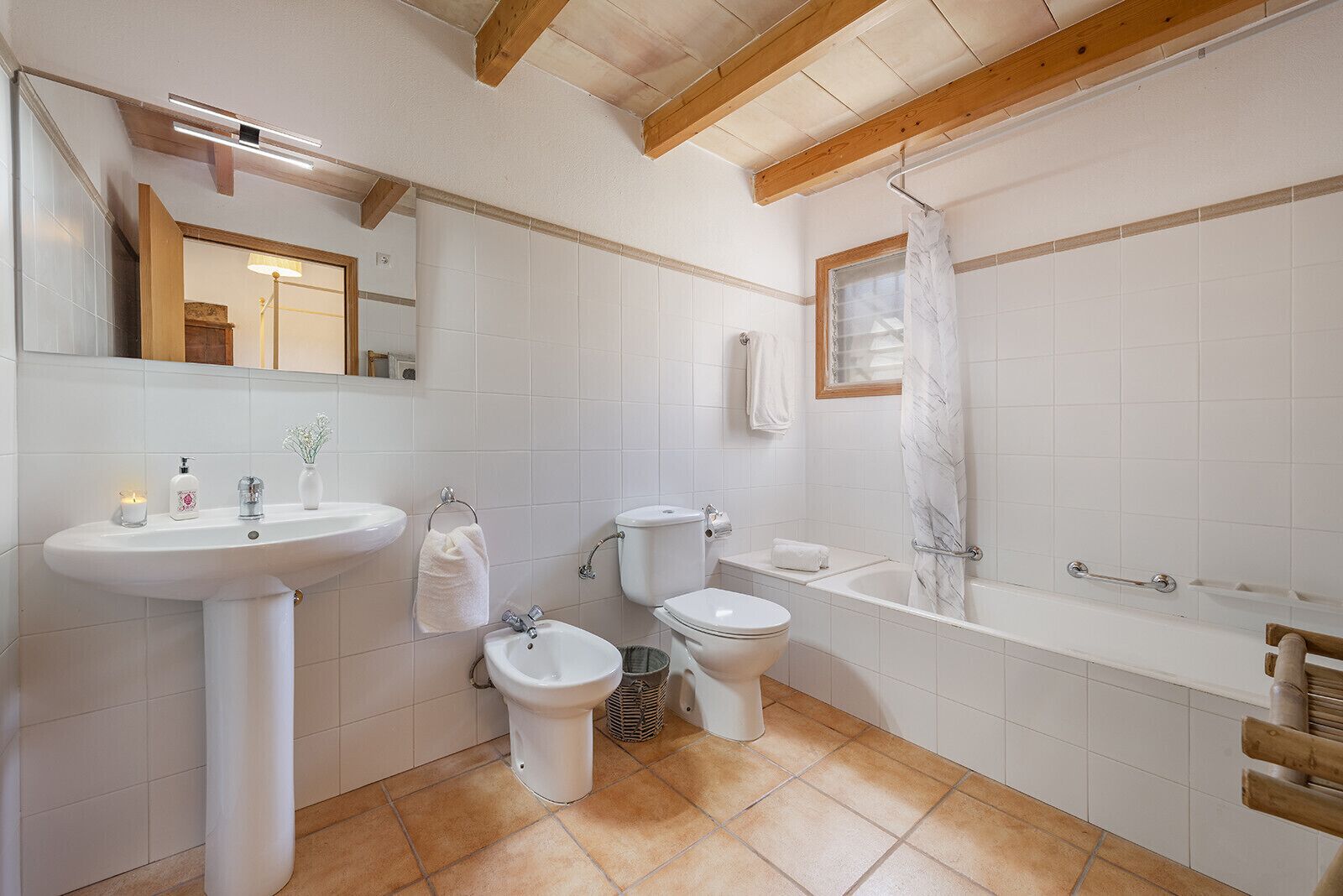 A bathroom with a sink, toilet, bidet, and bathtub.