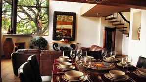A dining area with a table set for six, a fireplace, leather seating, and a staircase. - Serene Oasis in San Miguel de Allende 6-bedroom Villa With Hot Tub (San Miguel de Allende)