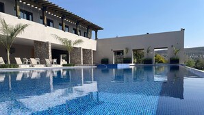 A clear blue infinity pool with lounge chairs and a stone facade building in the background. - Serene Oasis in San Miguel de Allende 6-bedroom Villa With Hot Tub (San Miguel de Allende)