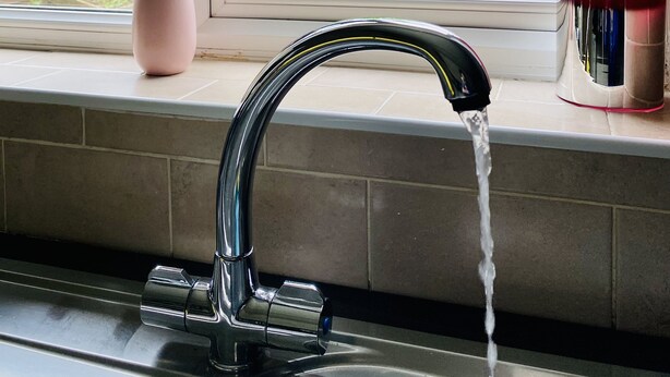 A kitchen sink with a modern faucet, a vase with flowers on the window sill, and a red glass container. - Stylish 2-Bedroom, Sleeps 5, Short walk to Durham City Centre, Wifi & Laundry (Durham)