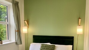 A neatly made bed with a green headboard, two bedside lamps, and a window with curtains. - Stylish 2-Bedroom, Sleeps 5, Short walk to Durham City Centre, Wifi & Laundry (Durham)