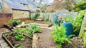 A garden with raised beds, a wooden bench, a greenhouse, and a compost bin. - Stylish 2-Bedroom, Sleeps 5, Short walk to Durham City Centre, Wifi & Laundry (Durham)