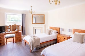 A hotel room with two beds, a wooden dresser, a television, and a fireplace. - Spacious 6 Bed Holiday Cottage w Sea Views (Bude)