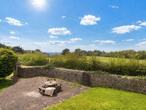 Eine Terrasse mit Tisch und Stühlen, umgeben von einer Steinmauer und Grünpflanzen.