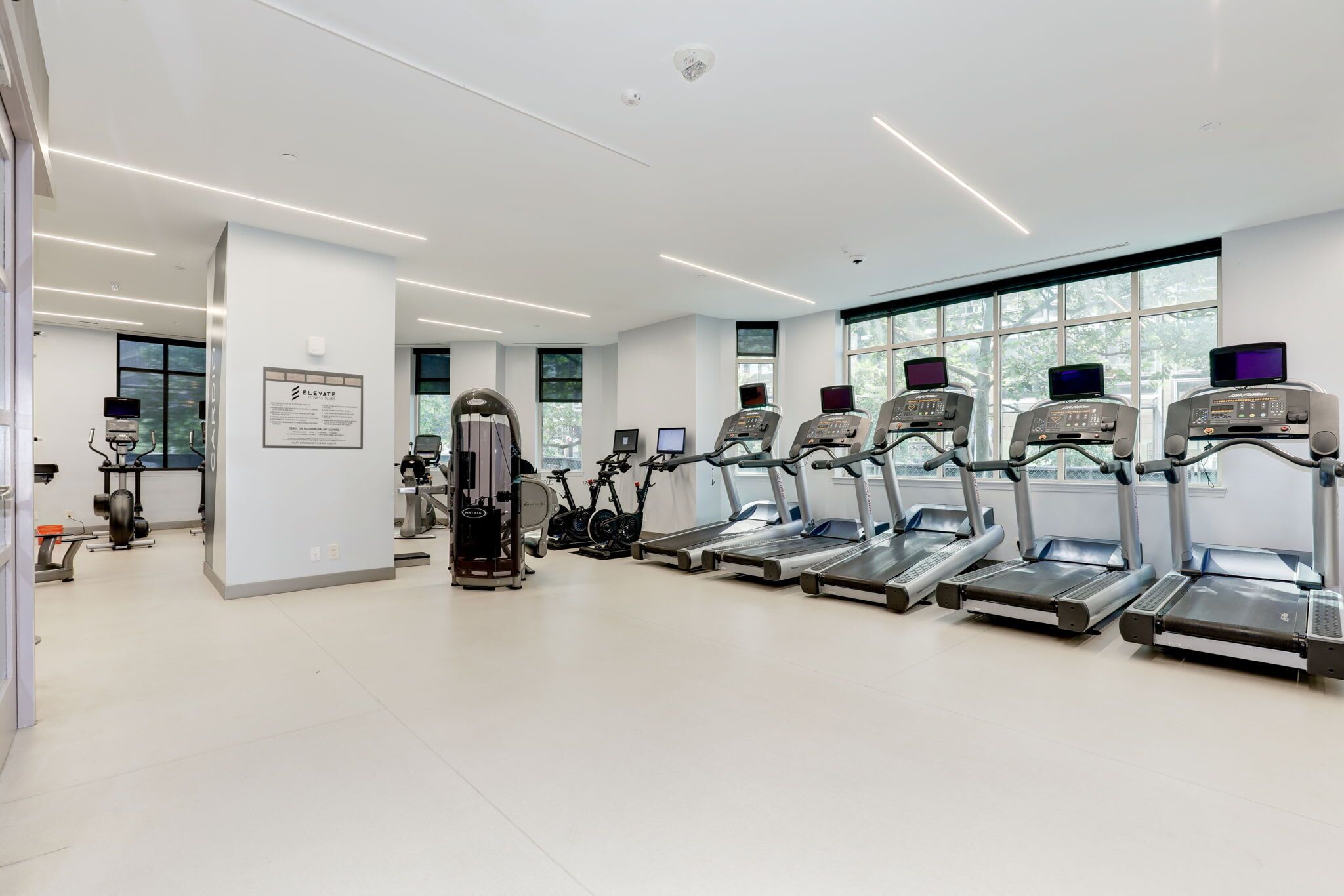 A modern gym with treadmills, elliptical machines, and weight equipment.