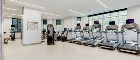 A modern gym with treadmills, elliptical machines, and weight equipment.