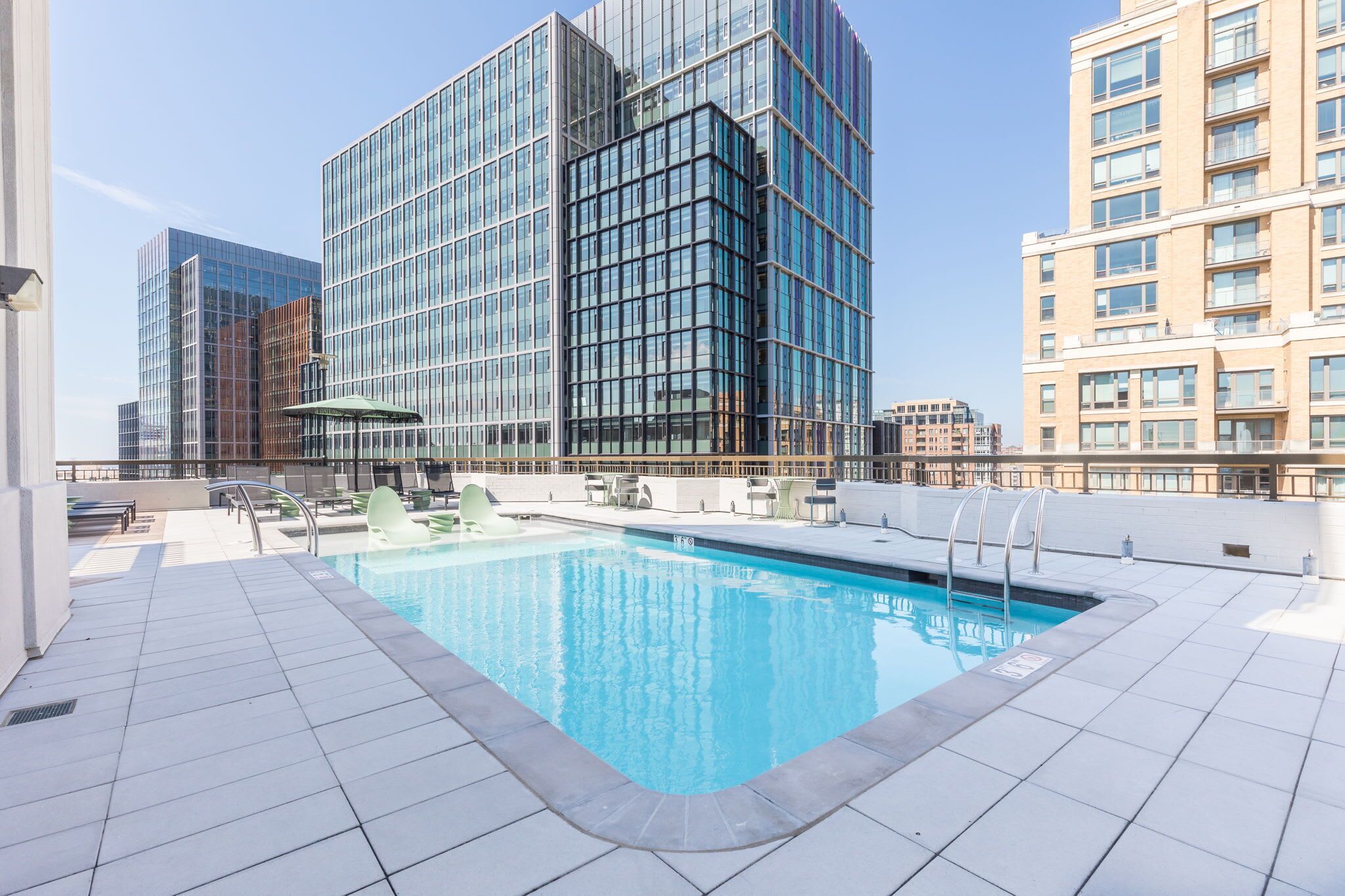 Zona de piscina en la azotea, con un edificio de cristal al fondo.