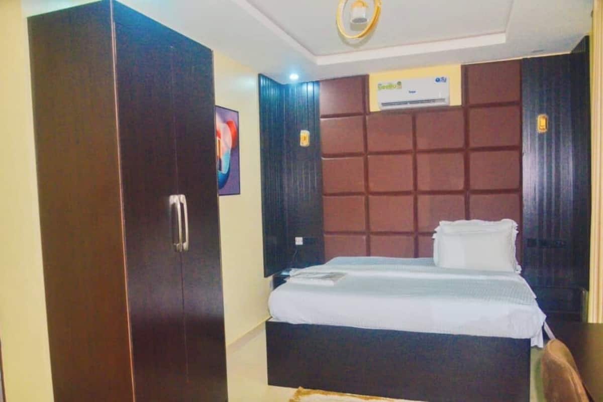 A hotel room with a large wardrobe, a bed with white bedding, and a wall-mounted air conditioning unit.