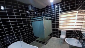 A modern bathroom with a freestanding bathtub, a glass-enclosed shower, a toilet, and a sink. - Kelvic Systems Apartments (Abuja)