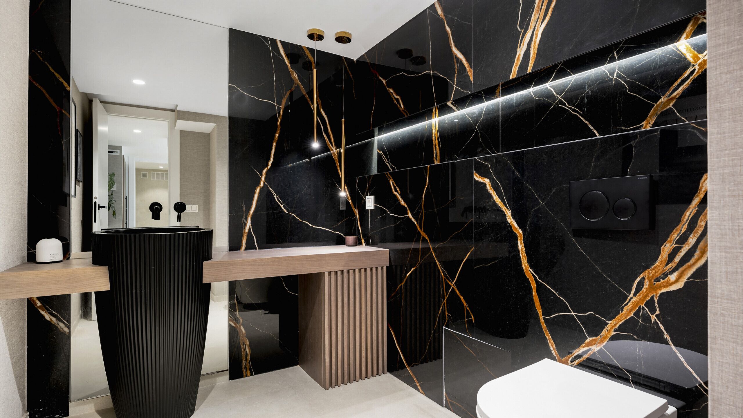 Une salle de bain moderne avec un meuble-lavabo en marbre noir, un panneau en bois et un lavabo blanc.