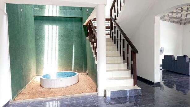 A modern interior with a staircase, a small pool area, and a seating area. - A A A Guest House (Dambulla)