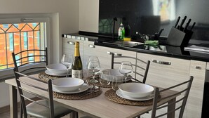 Une table à manger dressée avec de l’assiette blanche, des verres à vin et une bouteille de vin.