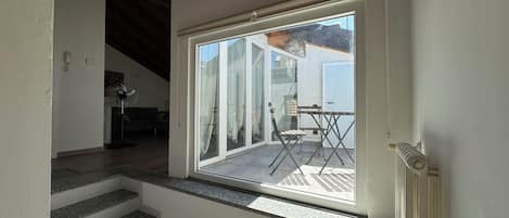 A staircase leading to a balcony with a table and chairs, a fan, and a view of the outside.