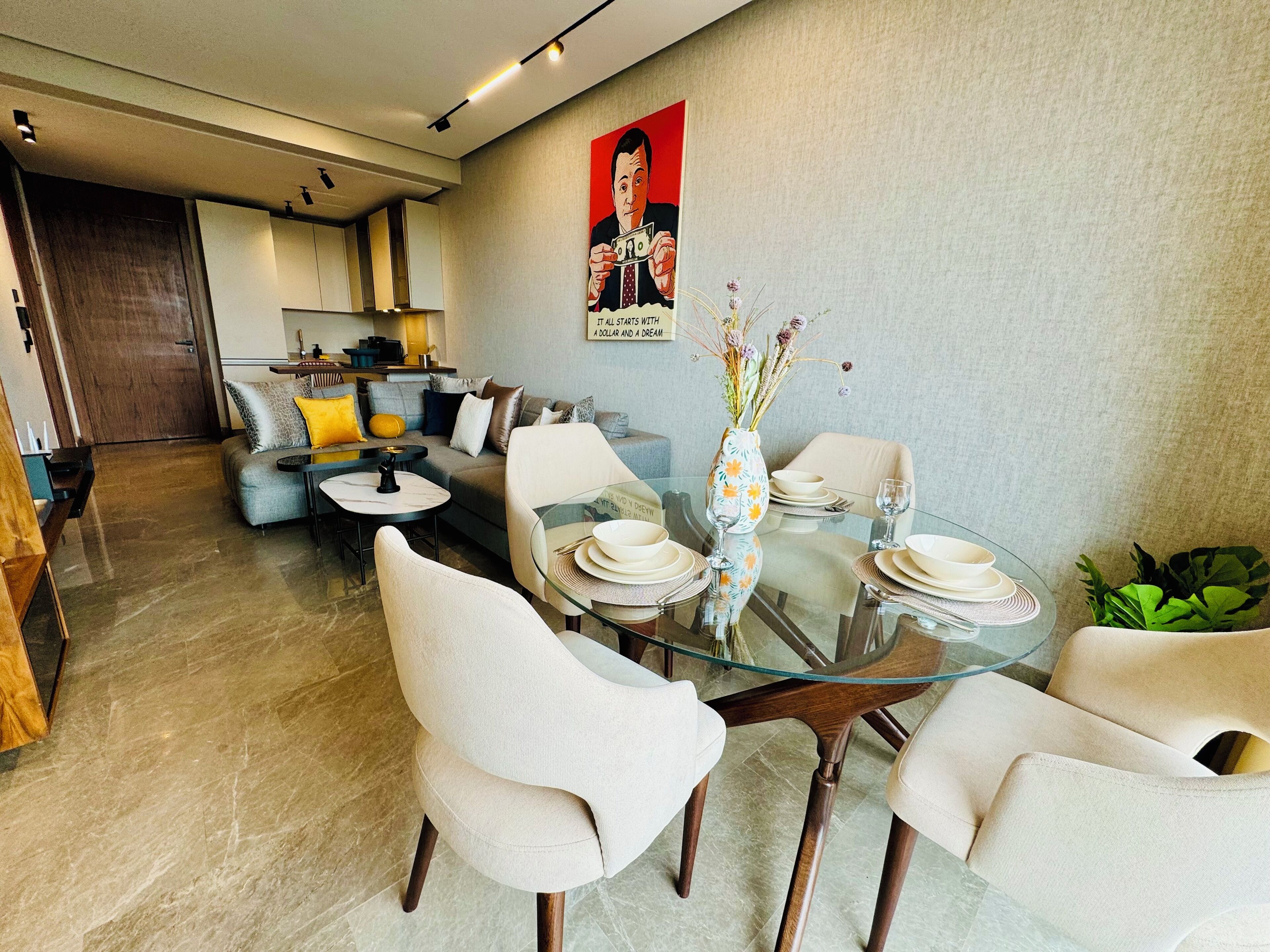 Un comedor moderno con una mesa de vidrio, sillas blancas y un jarrón decorativo.