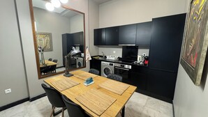 A compact kitchen with modern appliances, a dining area with a table and chairs, and a large mirror.