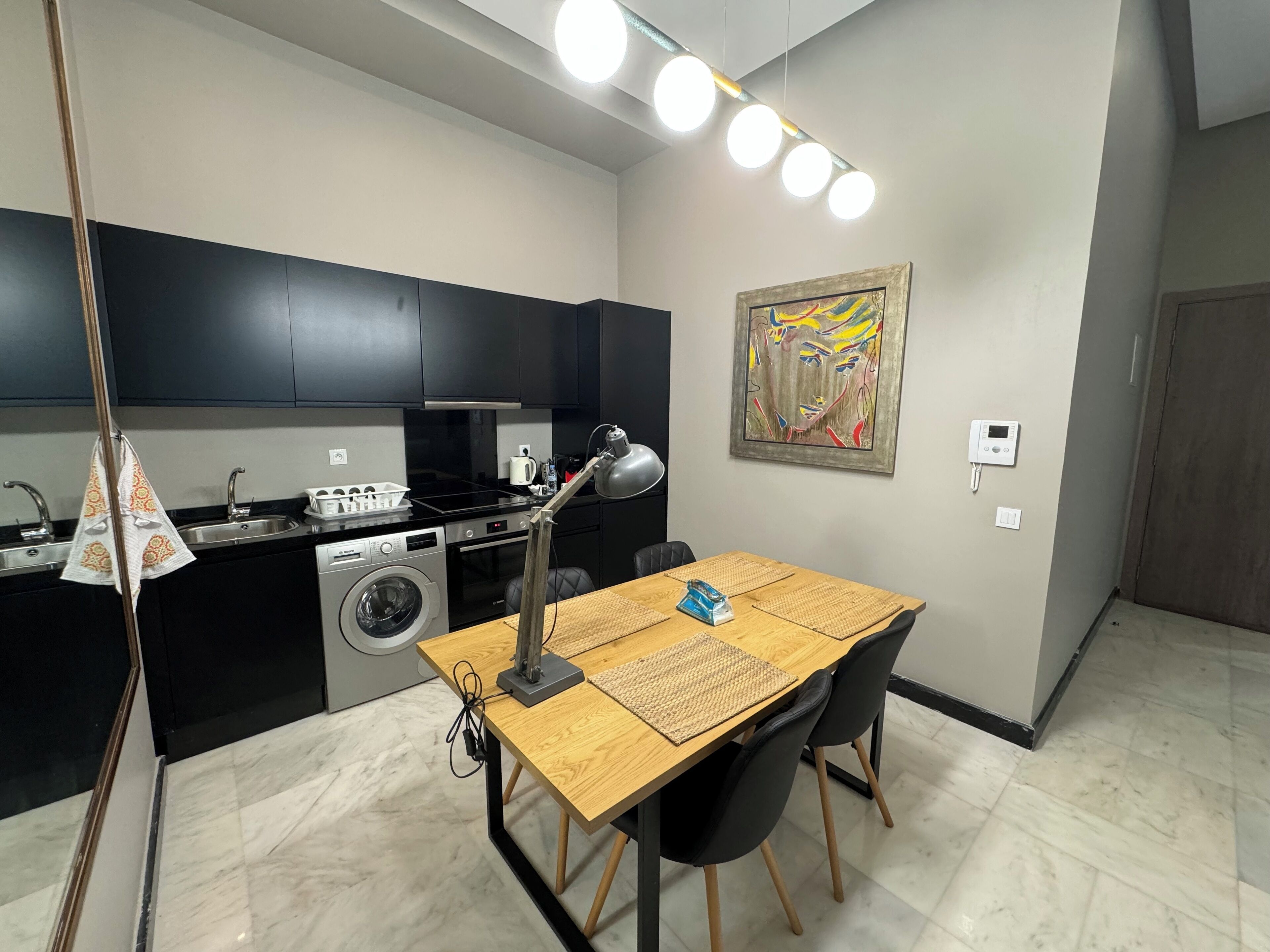Une cuisine compacte équipée d’un lave-linge, d’une cuisinière et d’un coin repas avec une table et des chaises.