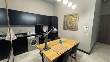 Une cuisine compacte équipée d’un lave-linge, d’une cuisinière et d’un coin repas avec une table et des chaises.
