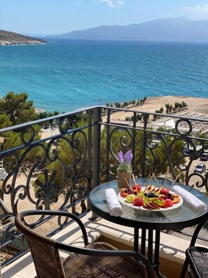 A balcony with a table set for a meal, overlooking a coastal view with mountains in the distance. - Ami Mar Hotel (Sarandë)