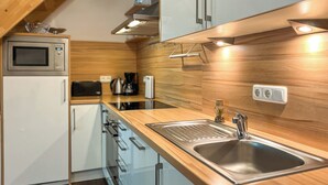 A modern kitchen with a wooden countertop, stainless steel sink, and built-in appliances.