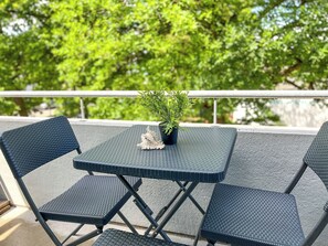Ein kleiner Tisch im Freien mit vier Stühlen, einem Blumentopf und einer Muschel.