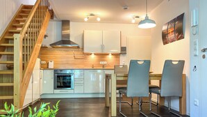 A modern kitchen with wooden cabinets, a built-in oven, and a dining area with two chairs.