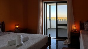 Hotelkamer met een bed, twee nachtkastjes met lampen, een balkon met uitzicht en een schuifdeur van glas.