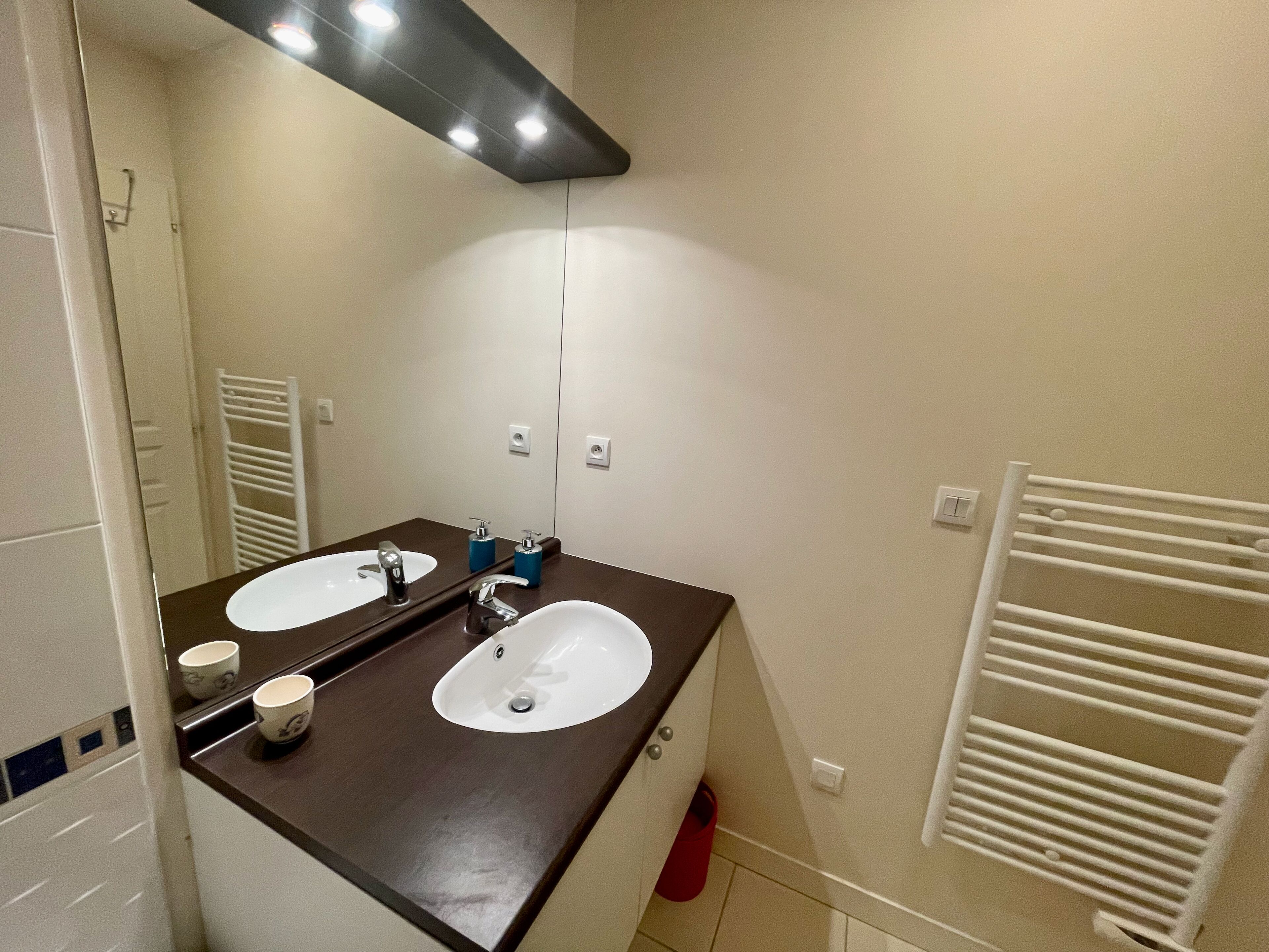 Un bagno con due lavandini, uno specchio e un portasciugamani.