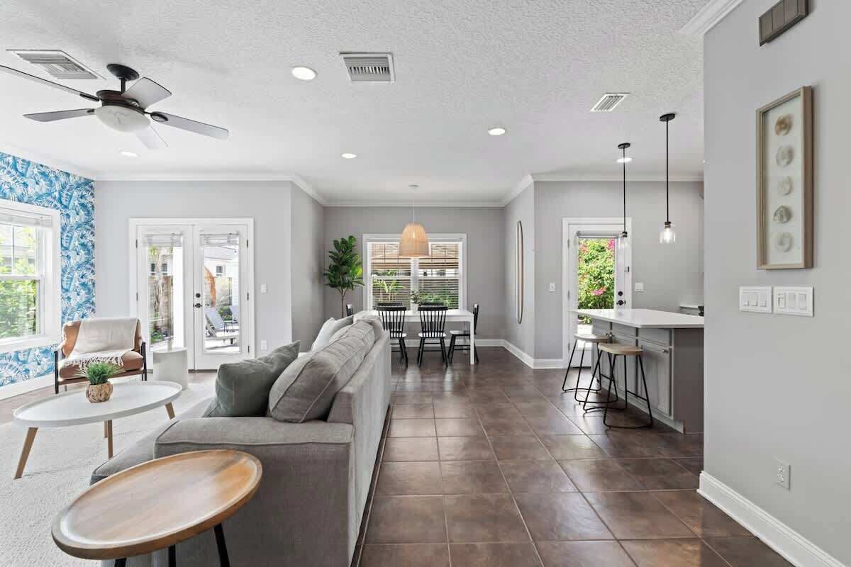 A spacious living room with a grey sofa, a round coffee table, and a ceiling fan.