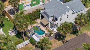 Una propiedad residencial con piscina, patio cubierto y jardín cercado.