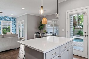 Cocina con una isla grande, armarios blancos e iluminación colgante.