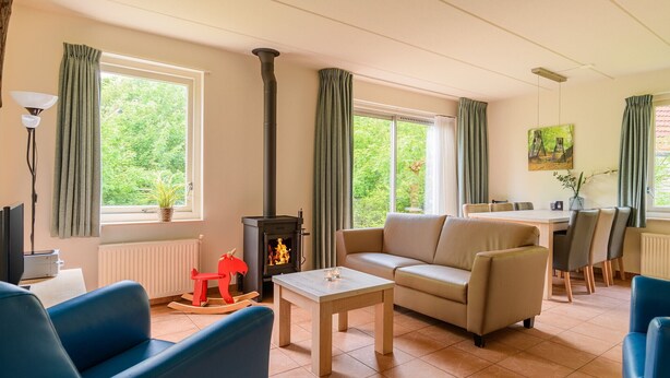 Un salon confortable avec un canapé, une petite table, une cheminée et un coin repas avec des chaises.