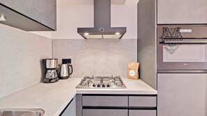 A modern kitchen with a gas stove, coffee maker, and a paper bag on the counter. - Semi-detached bungalow for 5 persons (Vlagtwedde)