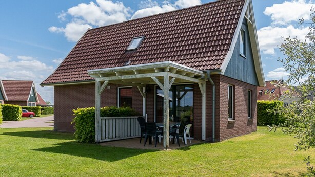 A house with a covered patio, brick exterior, and a red-tiled roof. - Detached 6-person bungalow (Vlagtwedde)